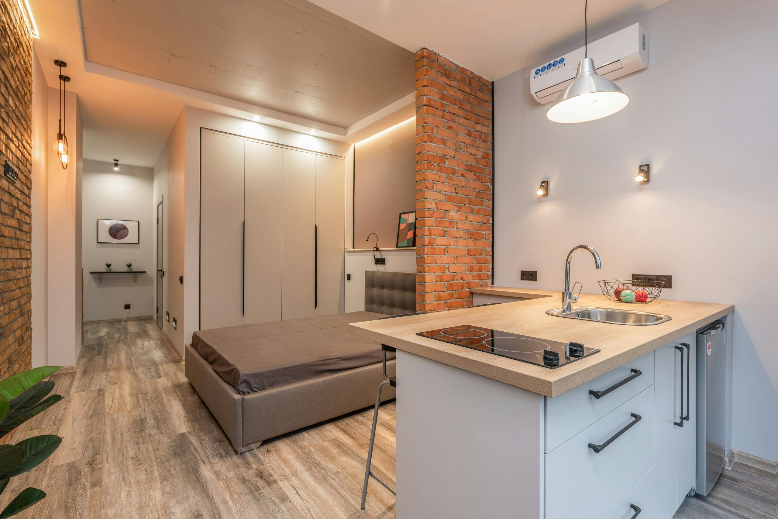 Miniature de cuisine avec appareils modernes et chambre derrière une cloison en briques dans un petit appartement de style loft