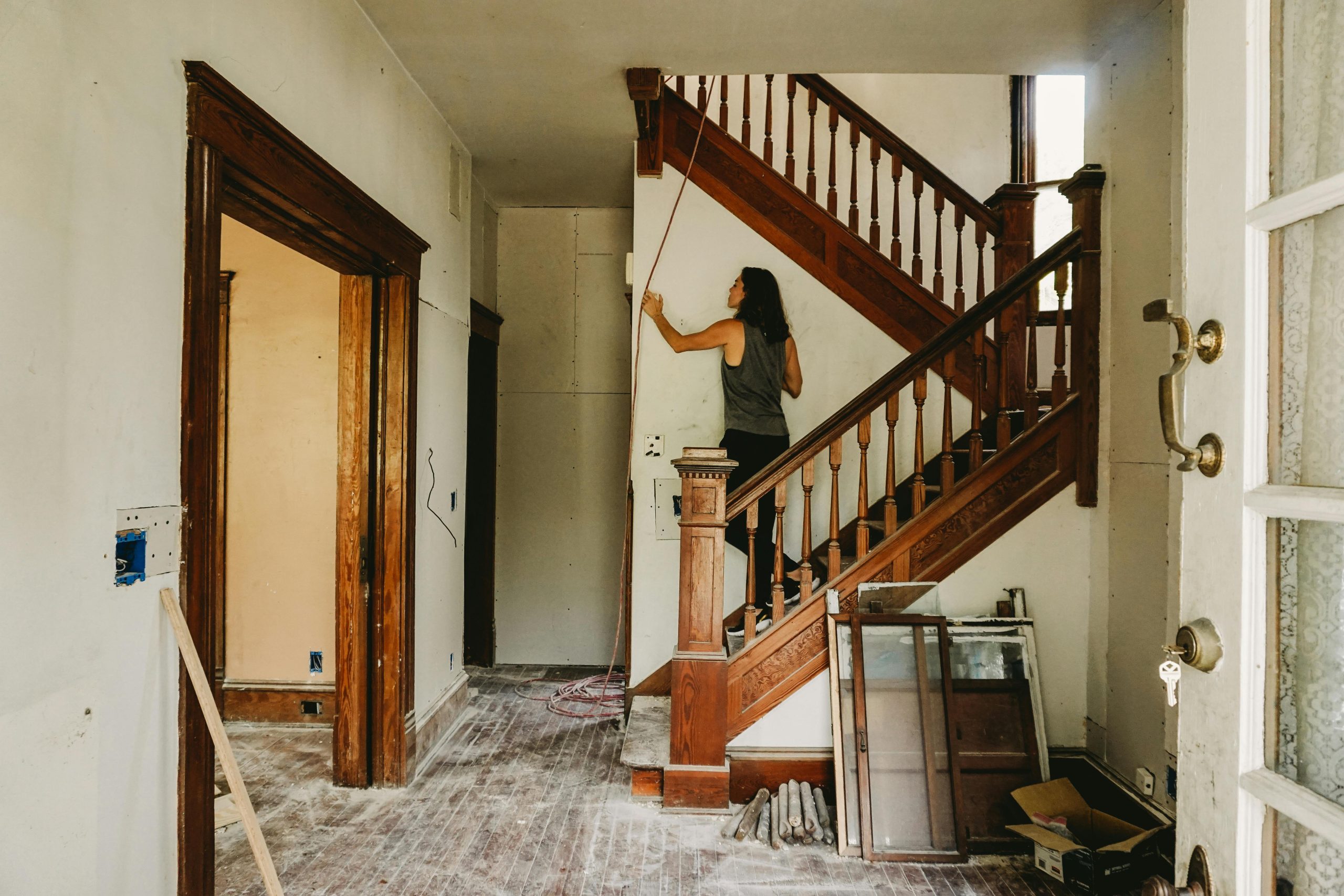 Une femme travaillant à la rénovation d'une maison mettant en avant un escalier en bois.