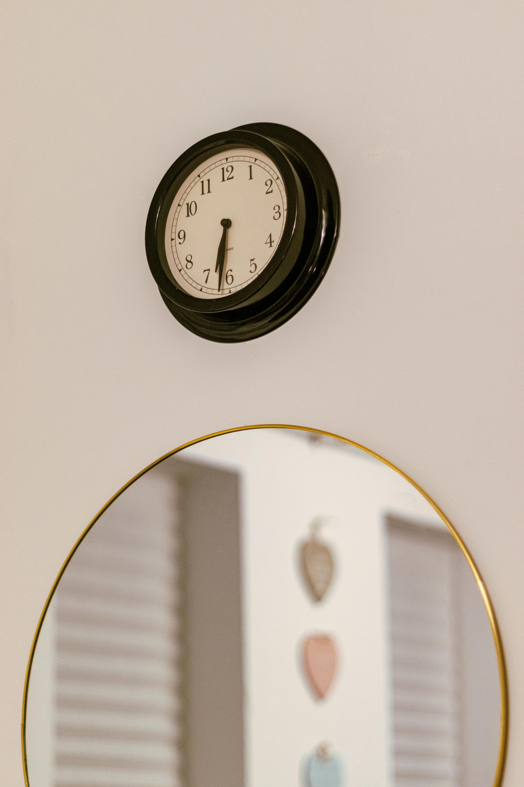 Stylish intérieur mural mettant en vedette une horloge noire classique au-dessus d'un miroir rond.