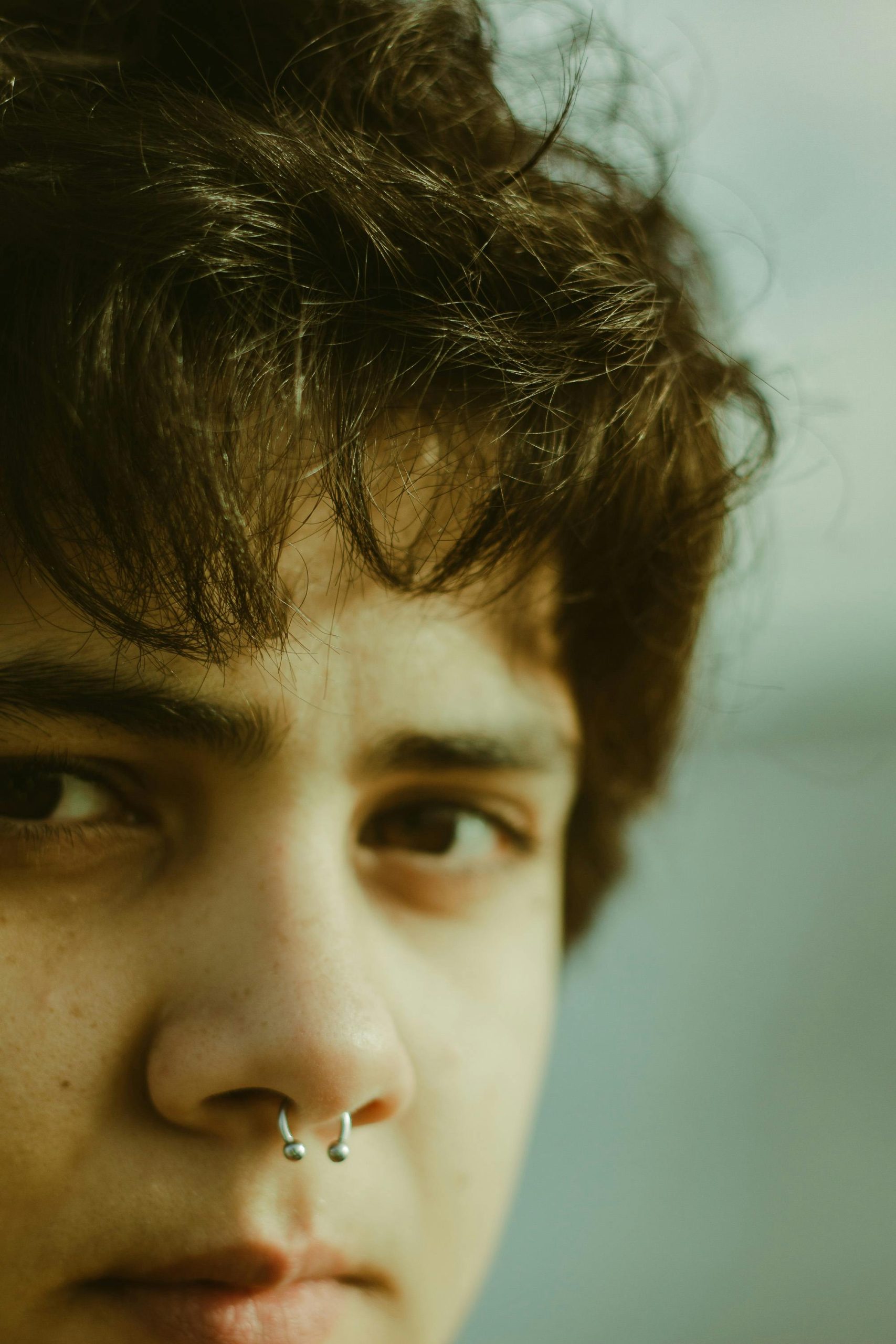 Soft focus gros plan sur un portrait d'une personne avec un piercing septal, capturé en lumière naturelle.