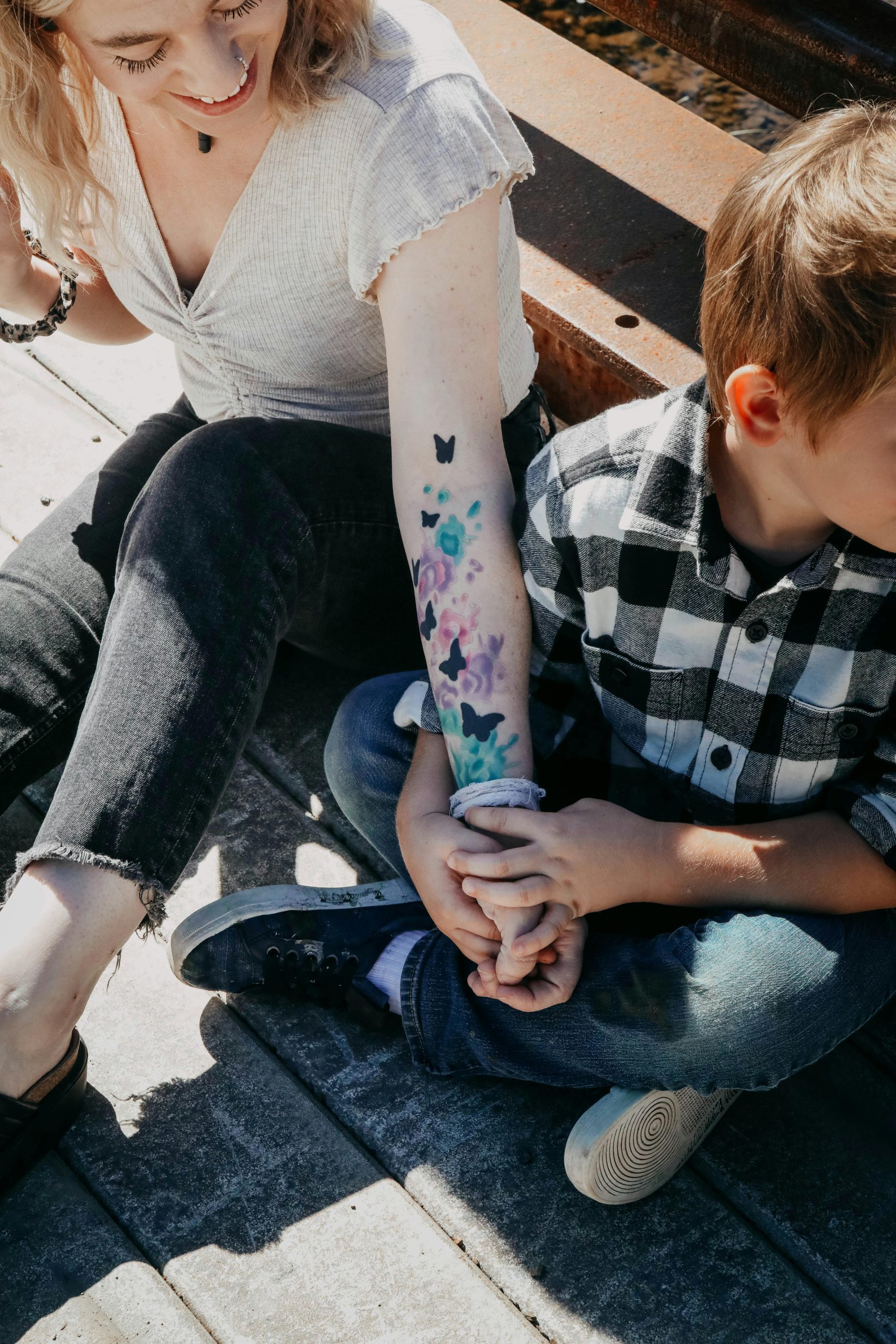 Une mère et un enfant assis en plein air à Port Crane, NY, se tenant par la main et profitant d'une journée ensoleillée.