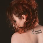 Artistic portrait of a redhead woman with back tattoo in a studio setting. Portrait artistique d'une femme rousse avec un tatouage dans le dos dans un cadre de studio.