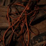 Close-up view of tangled old cords with a reddish hue, creating an industrial vibe. Vue rapprochée de vieux câbles emmêlés avec une teinte rougeâtre, créant une ambiance industrielle.