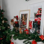 Cozy Christmas mantel with festive decorations, framed art and a holiday tree. Cheminée de Noël confortable avec des décorations festives, de l'art encadré et un sapin des fêtes.