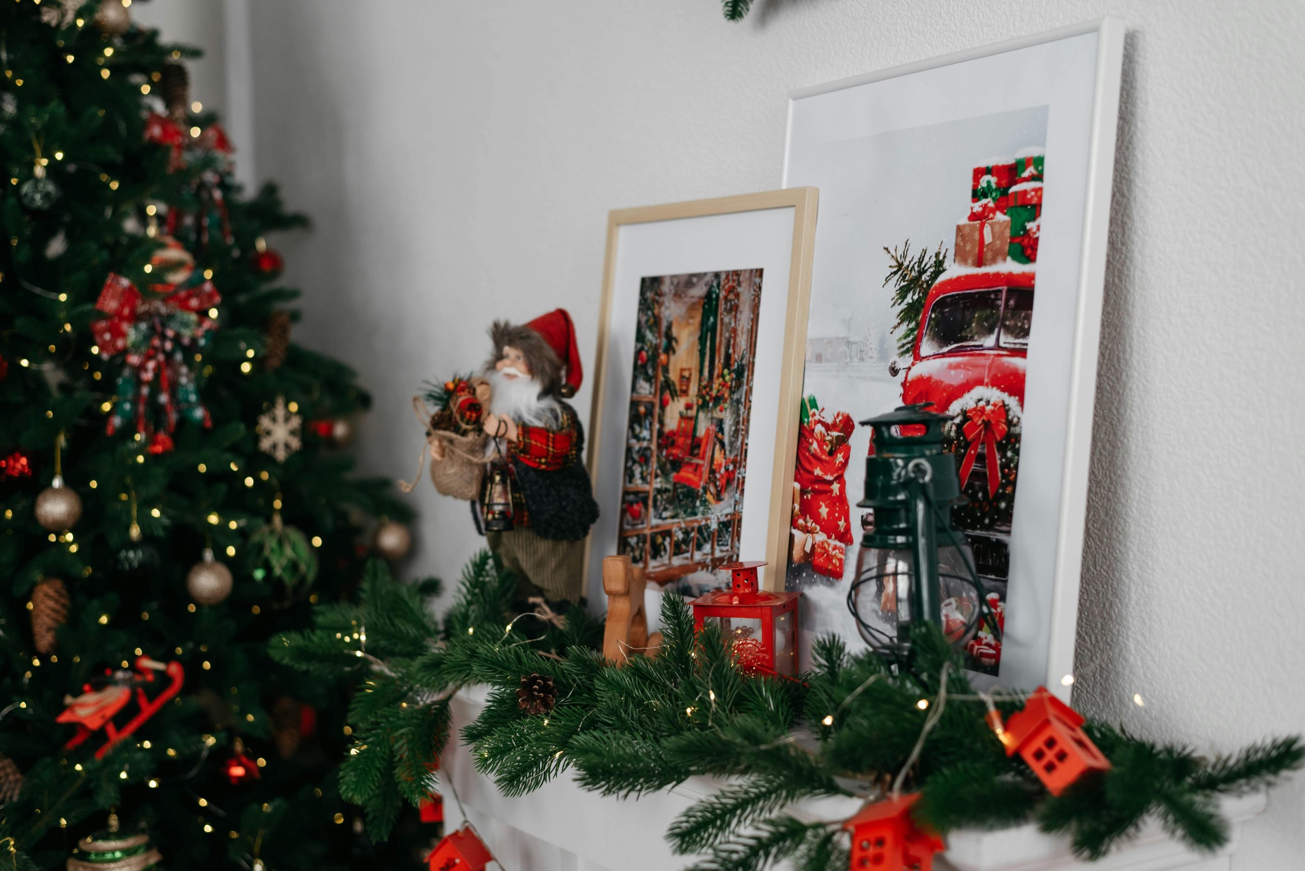 Cozy Christmas mantel with festive decorations, framed art and a holiday tree. Cheminée de Noël confortable avec des décorations festives, de l'art encadré et un sapin des fêtes.