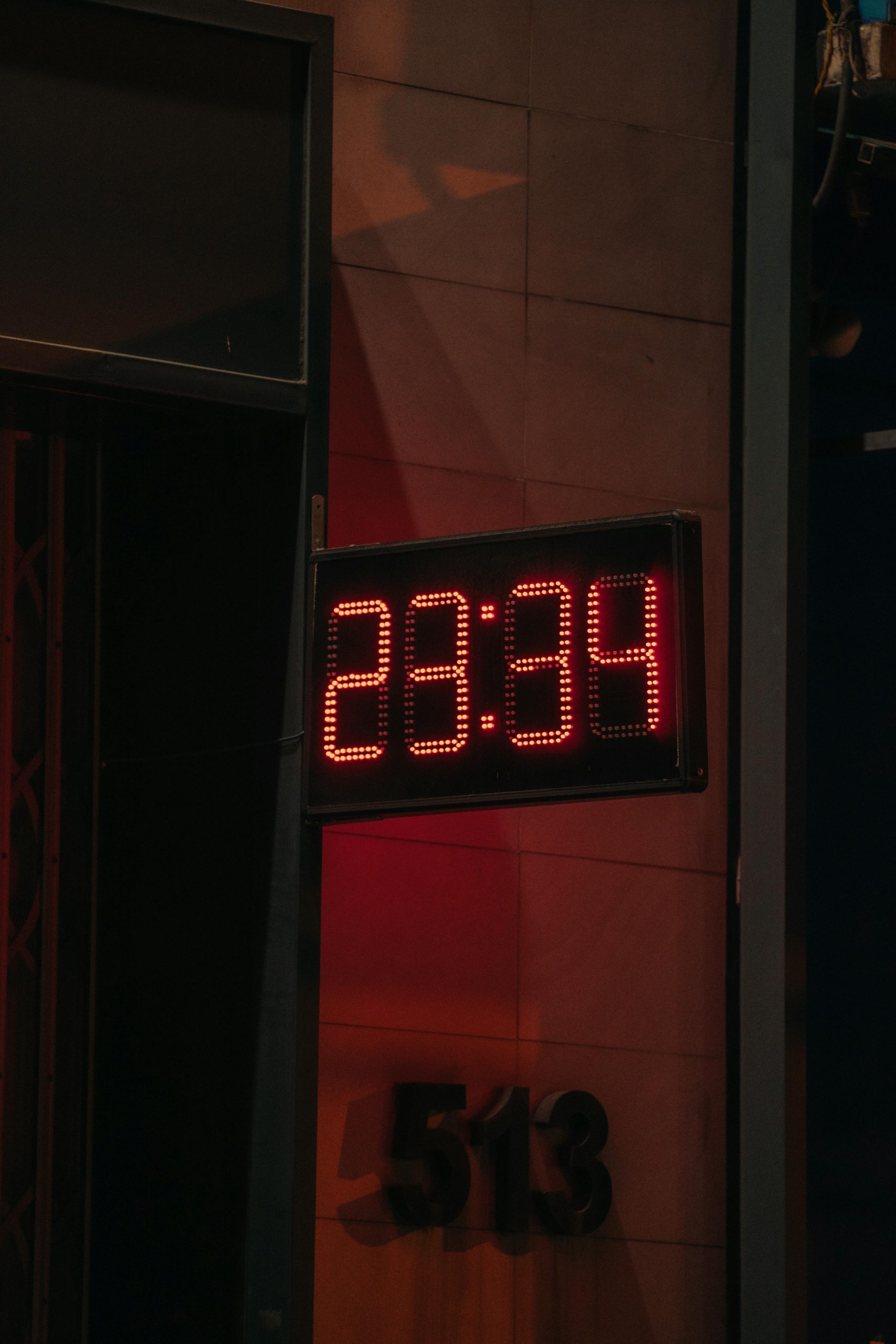 Photo d'une horloge numérique rouge affichant l'heure sur un bâtiment urbain, cadre nocturne.