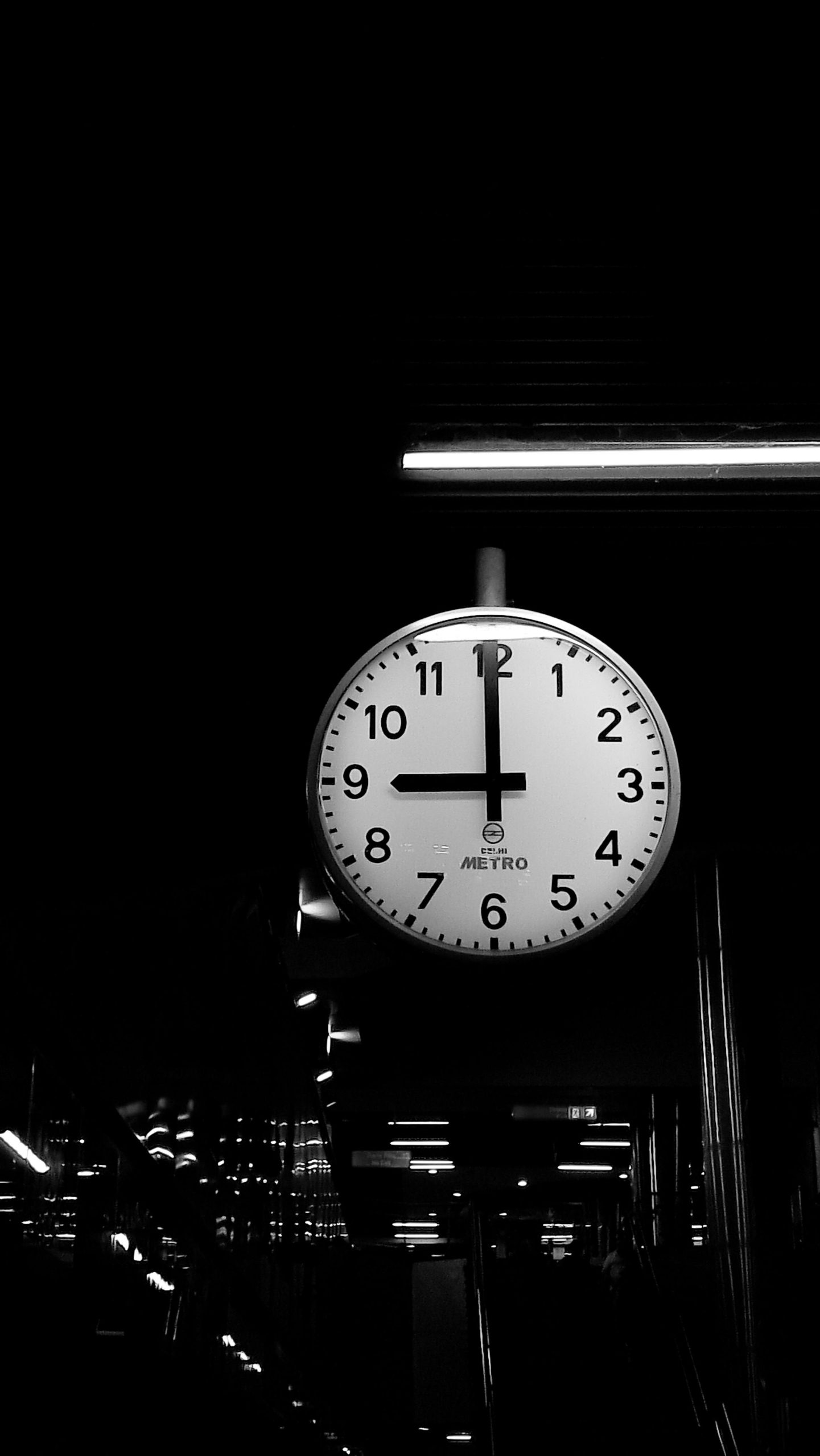 Black and white photo of an analog clock at a Delhi Metro station. Photo en noir et blanc d'une horloge analogique à la station de métro de Delhi.