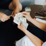 Close-up of hands counting cash in an indoor setting, conveying transaction theme. Gros plan de mains comptant de l'argent liquide dans un intérieur, véhiculant un thème de transaction.