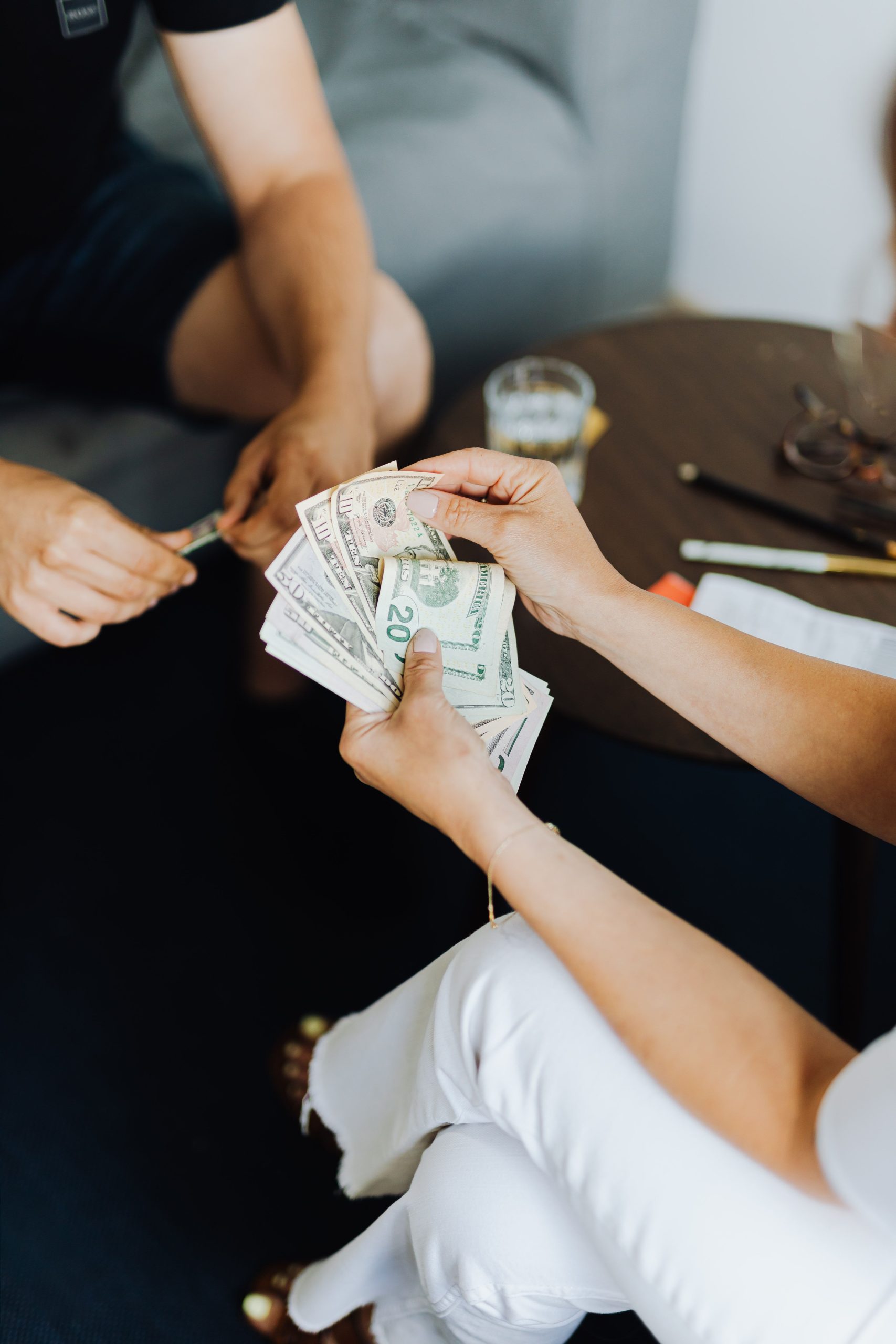 Close-up of hands counting cash in an indoor setting, conveying transaction theme. Gros plan de mains comptant de l'argent liquide dans un intérieur, véhiculant un thème de transaction.