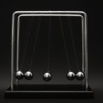 Newton's cradle for physics principles and motion study on a dark background. Le berceau de Newton pour l'étude des principes de physique et du mouvement sur un fond sombre.