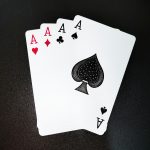 A close-up shot of four aces on a black background, showcasing symbols of poker and gambling. Gros plan de quatre as sur fond noir, mettant en évidence les symboles du poker et des jeux d'argent.