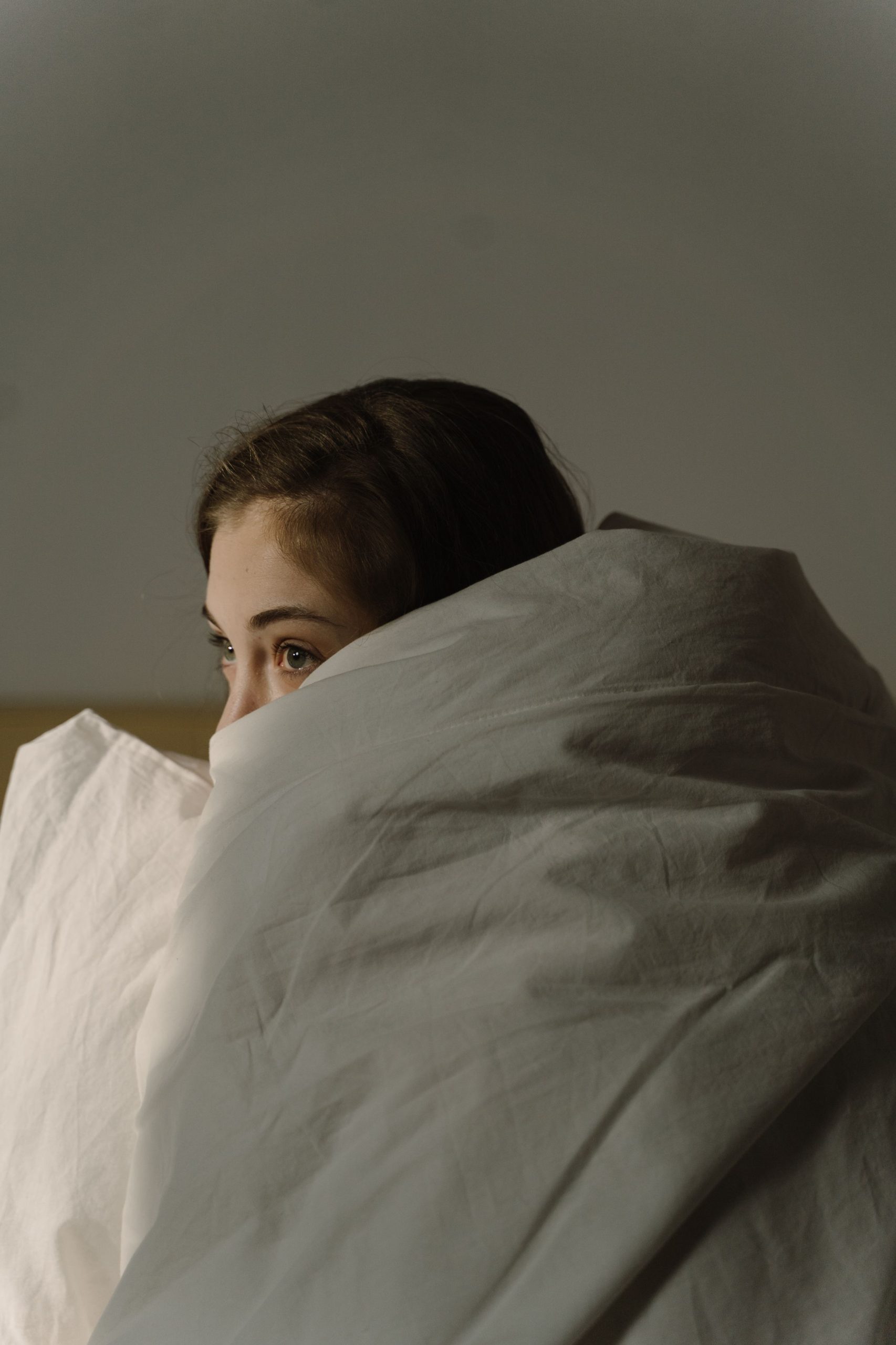 Woman wrapped in a white blanket, creating a serene and cozy bedroom atmosphere. Une femme enveloppée dans une couverture blanche, créant une atmosphère de chambre sereine et confortable.