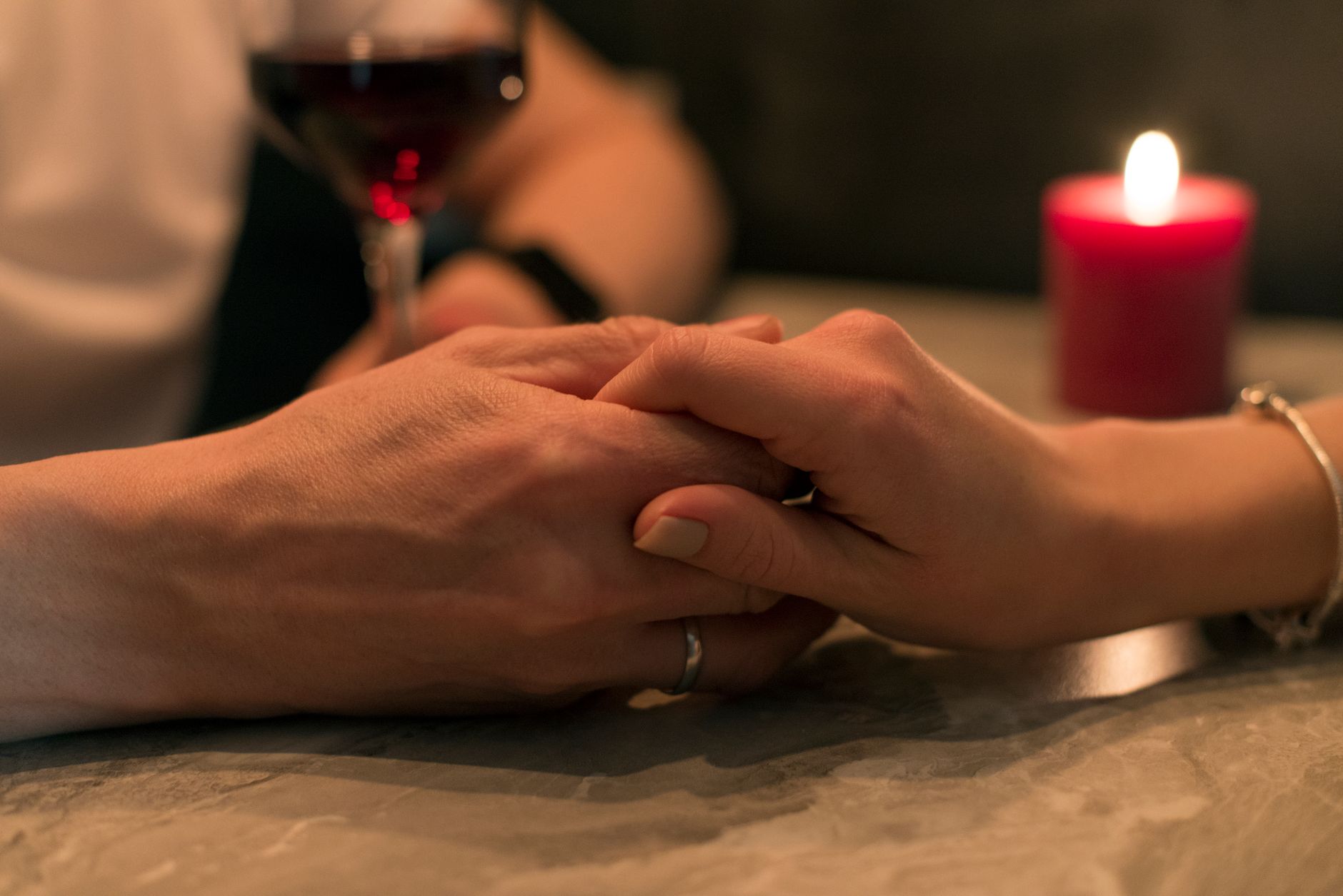Couple se tenant la main à la lueur d’une bougie