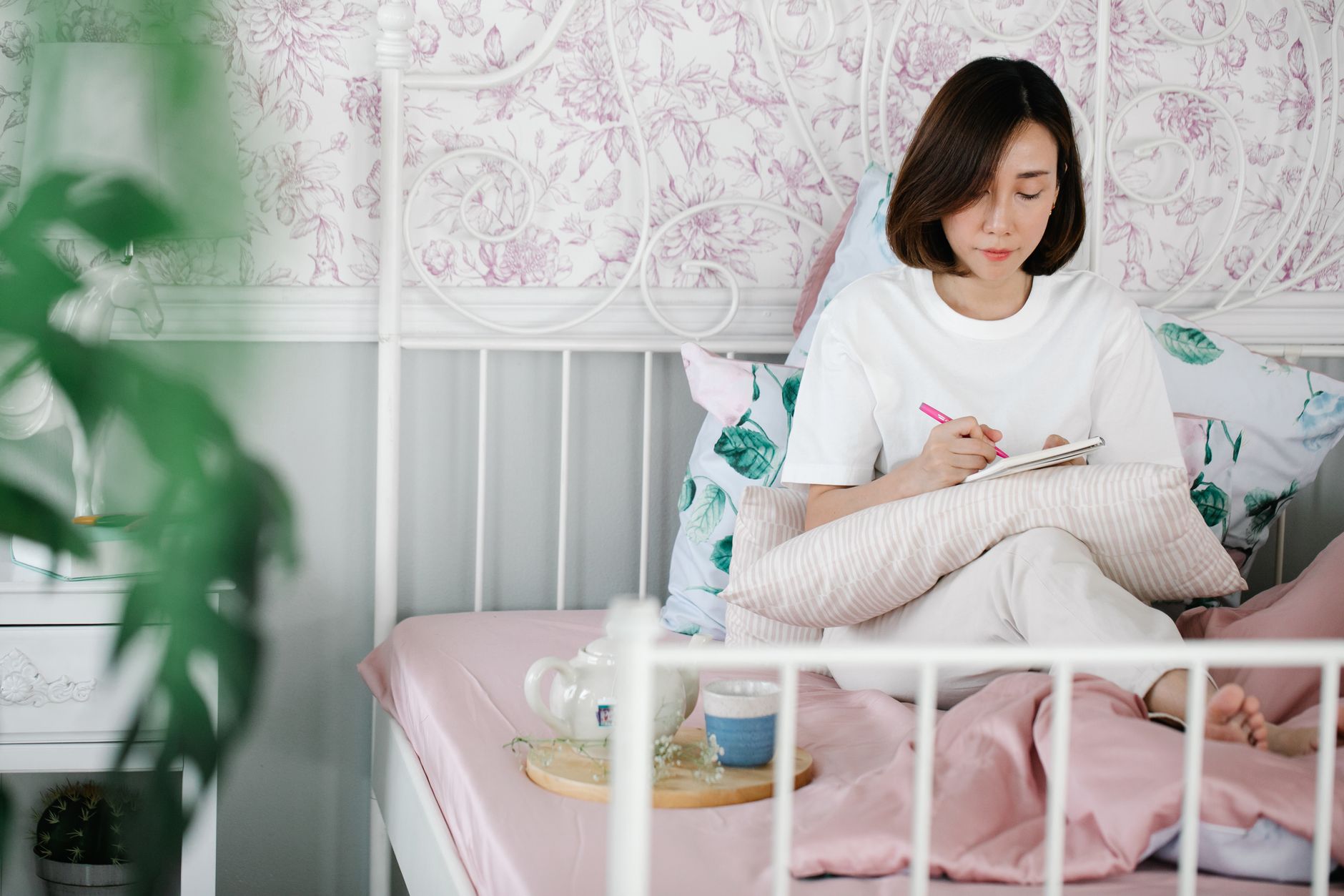 Femme écrivant dans un carnet sur son lit le matin
