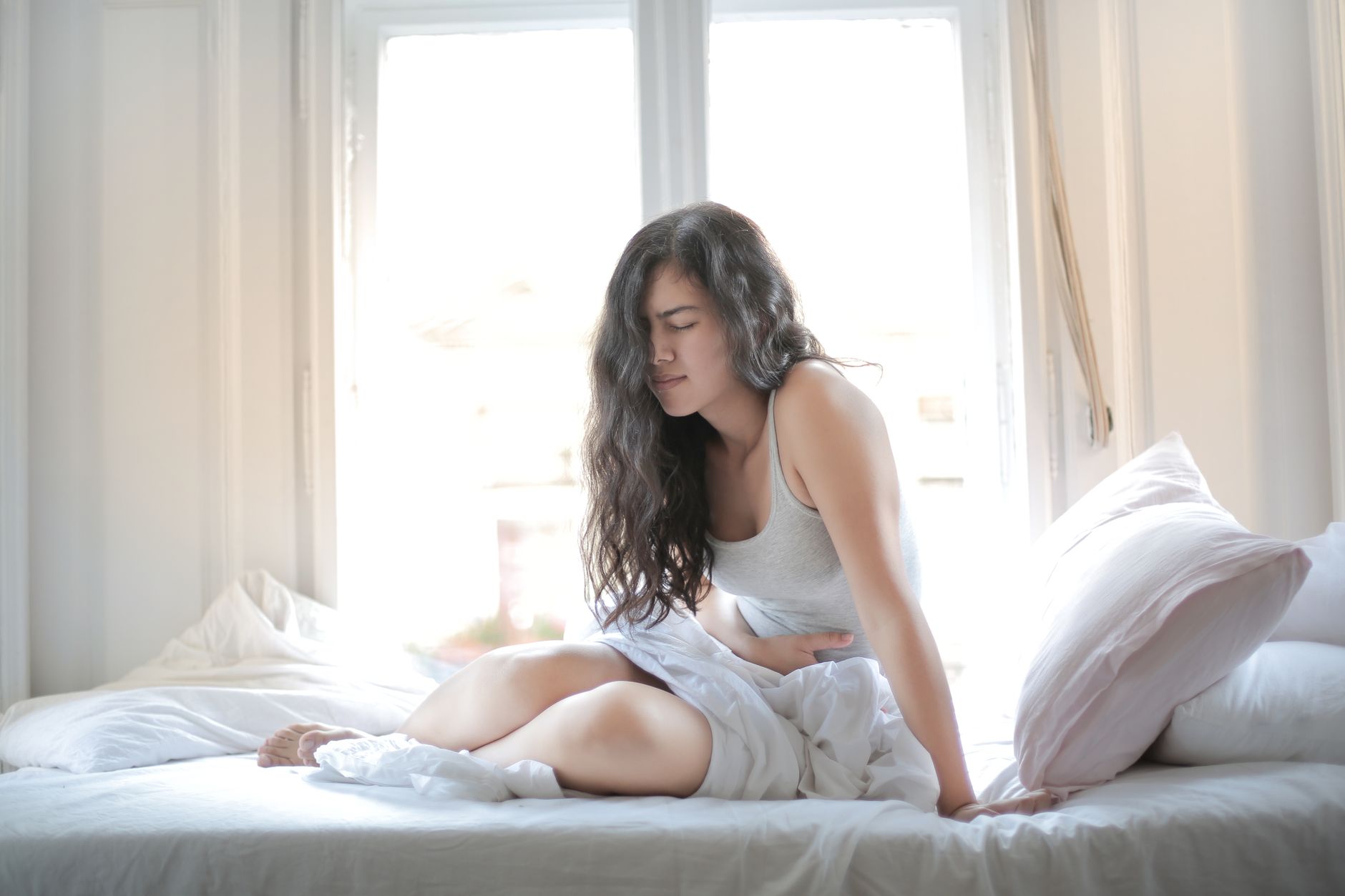 Femme assise, douleur au ventre au lit