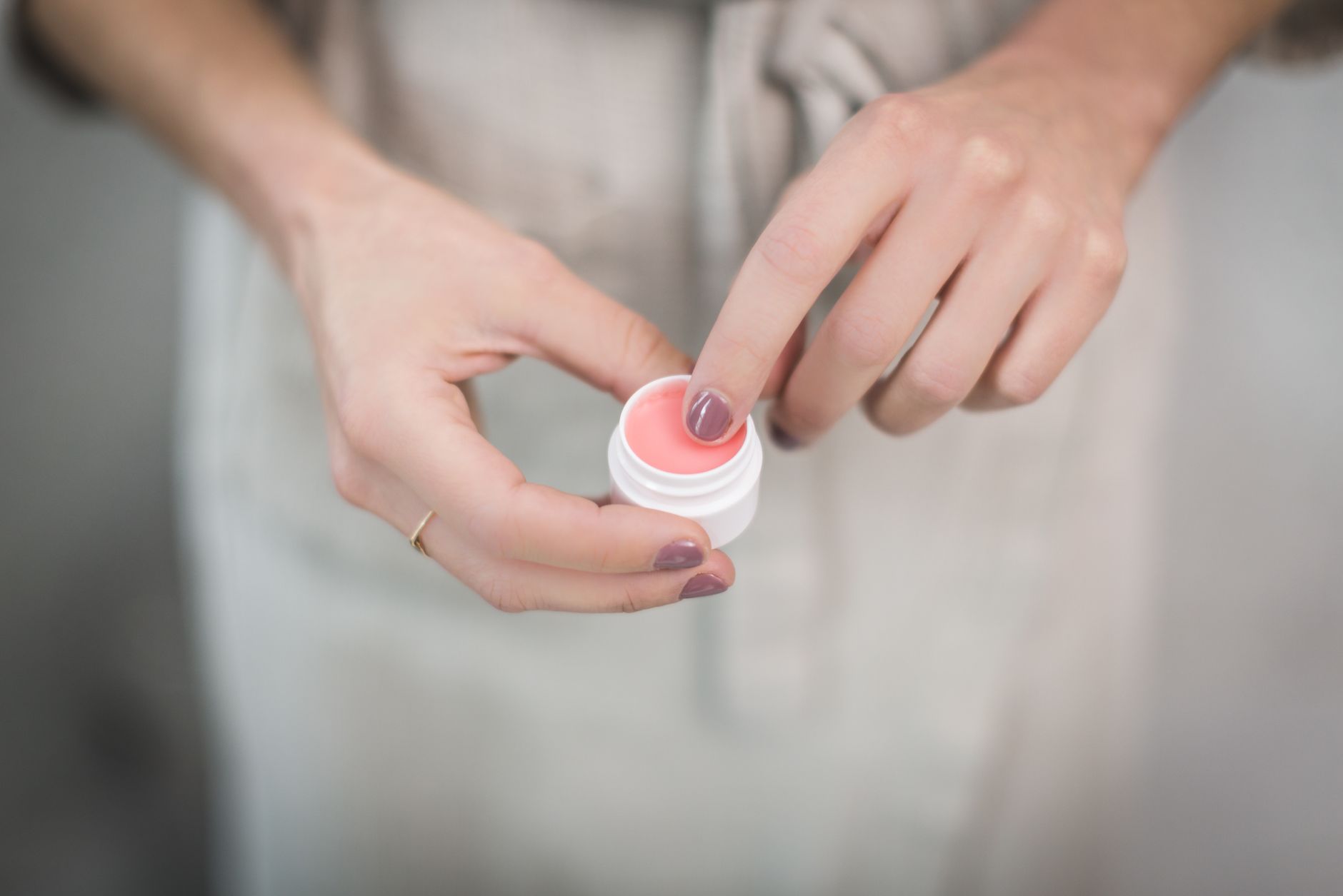 Mains appliquant un baume à lèvres rosé