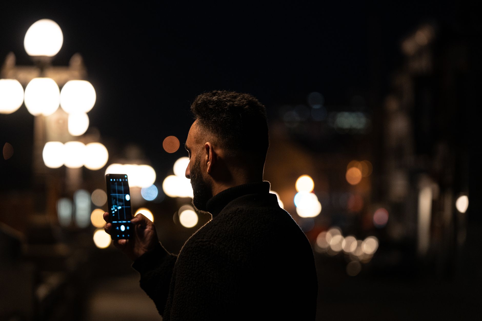 Homme qui utilise son téléphone la nuit en ville