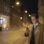 Homme qui consulte son téléphone la nuit dans la rue