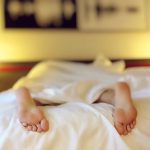 Pieds sous un drap blanc dans une chambre la nuit