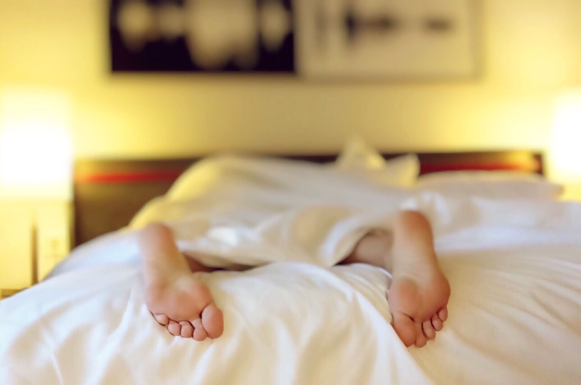 Pieds sous un drap blanc dans une chambre la nuit