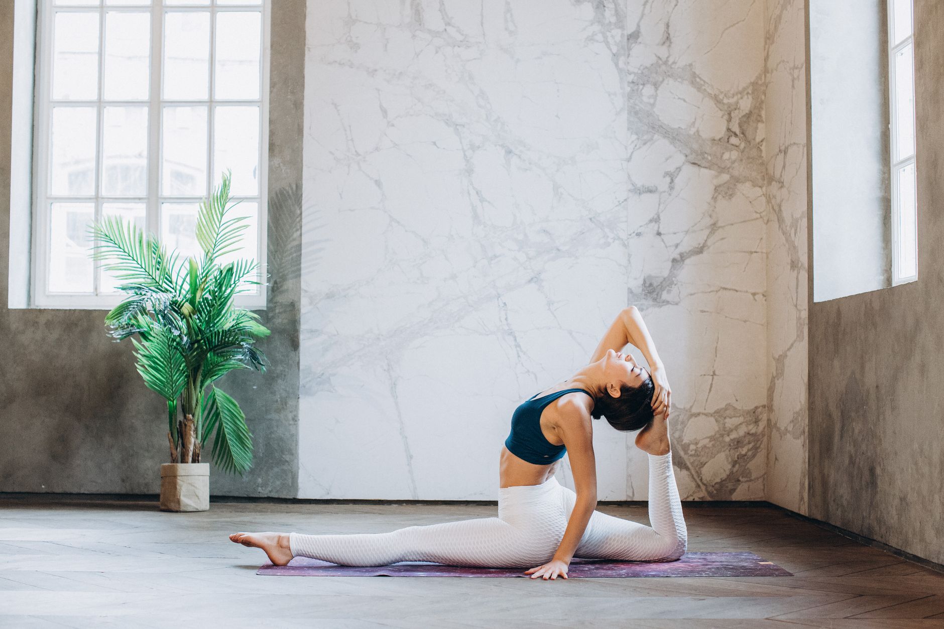 Femme en posture de yoga hanumanasana en intérieur