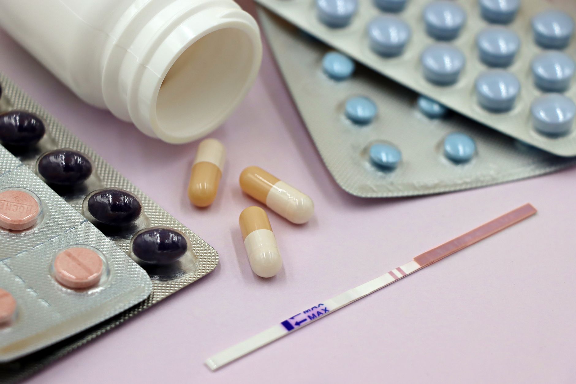 Test de grossesse positif posé à côté de comprimés