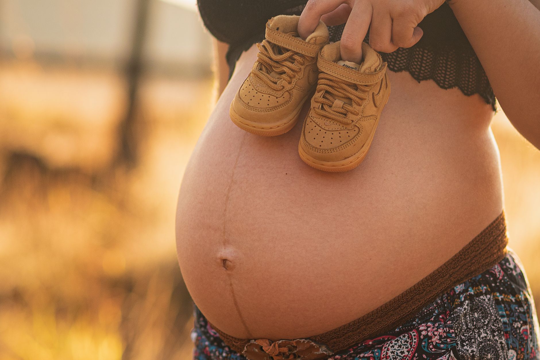 Femme enceinte tenant des chaussons de bébé