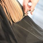 Coiffeur en train de couper des cheveux blonds avec des ciseaux dans un salon