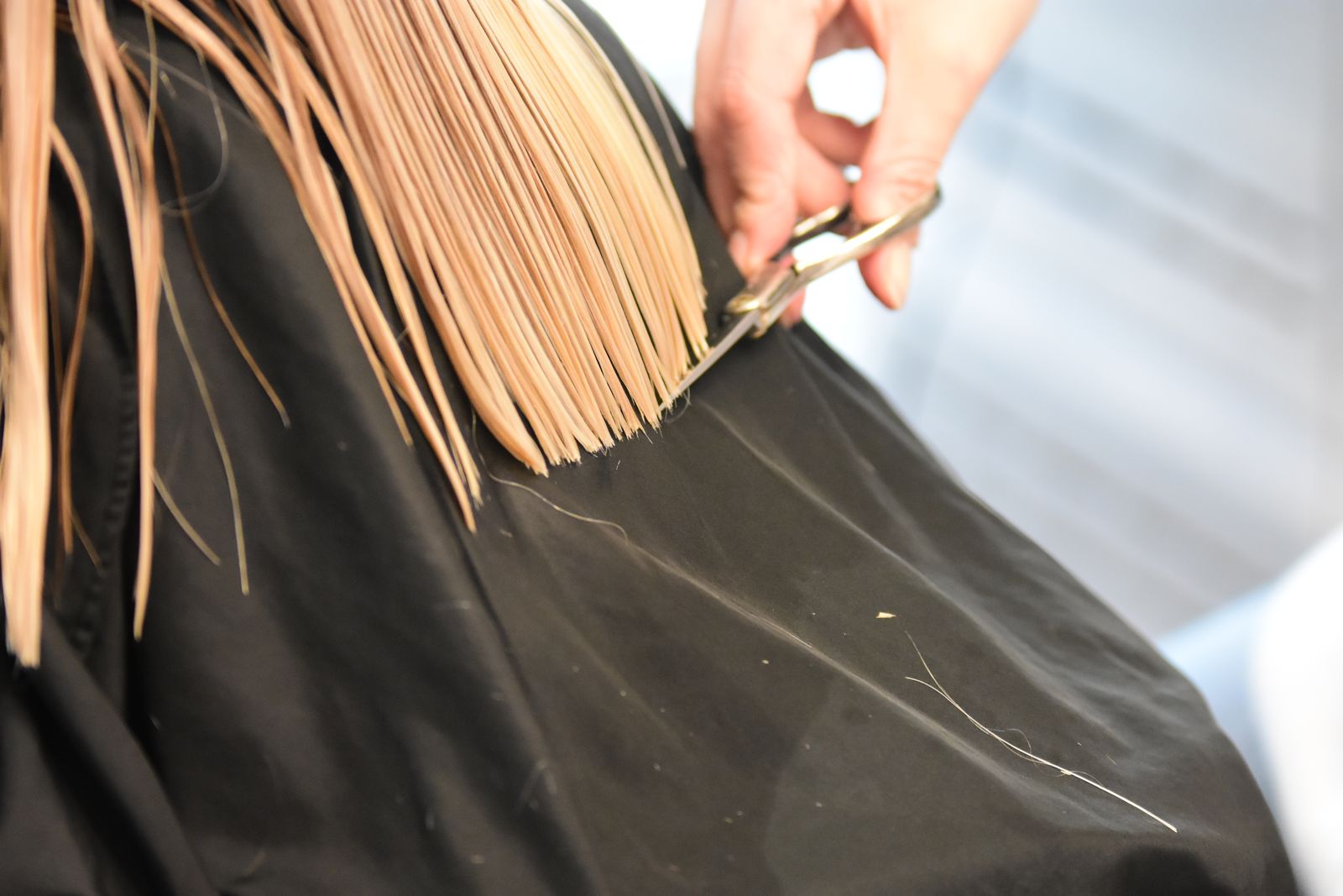 Coiffeur en train de couper des cheveux blonds avec des ciseaux dans un salon