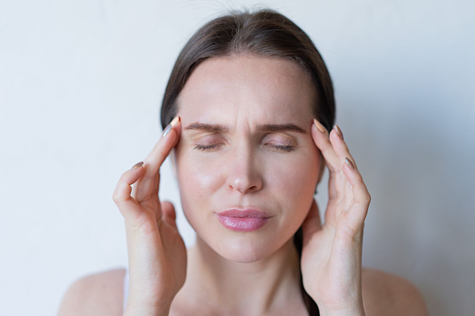 Femme les yeux fermés qui masse ses tempes pour calmer une douleur