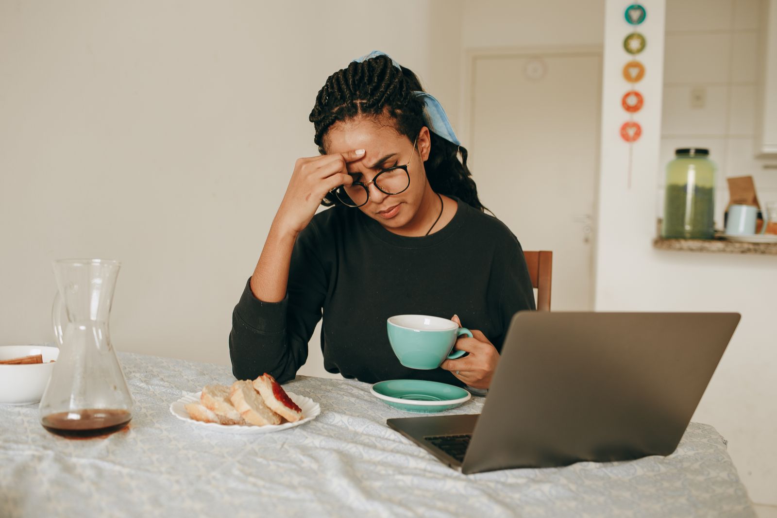 Femme attablée devant une tasse, la main sur le front