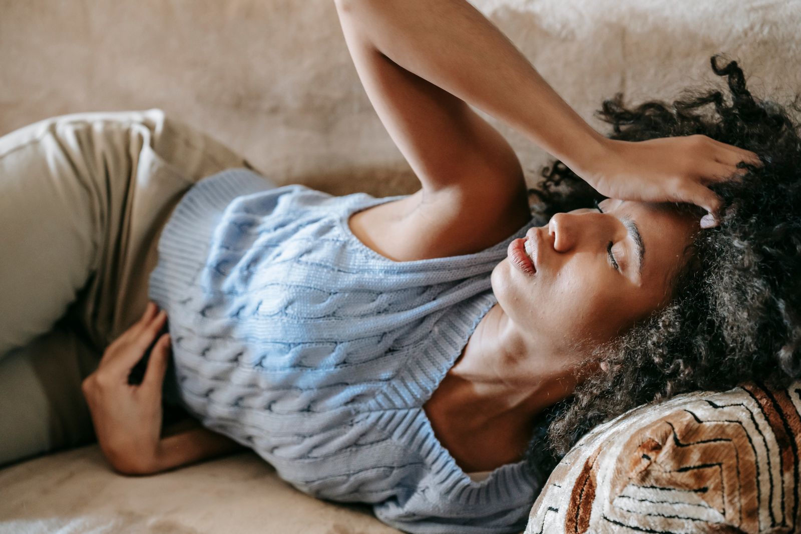 Jeune femme allongée sur un canapé, la main posée sur le front