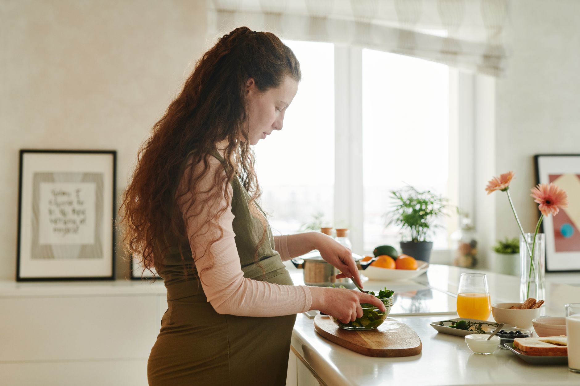 Femme enceinte qui prépare un repas dans sa cuisine