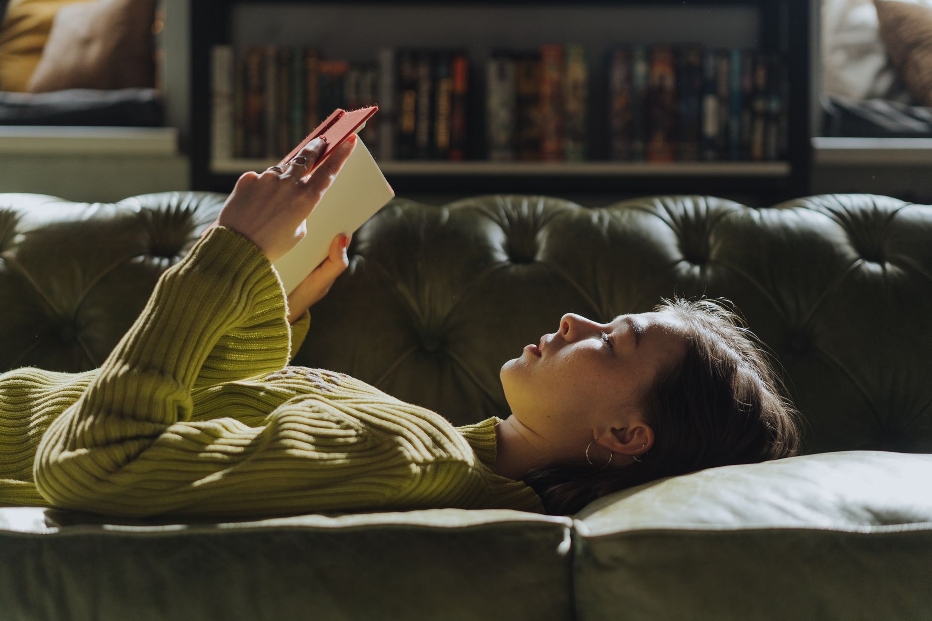Jeune femme allongée sur un canapé avec un livre