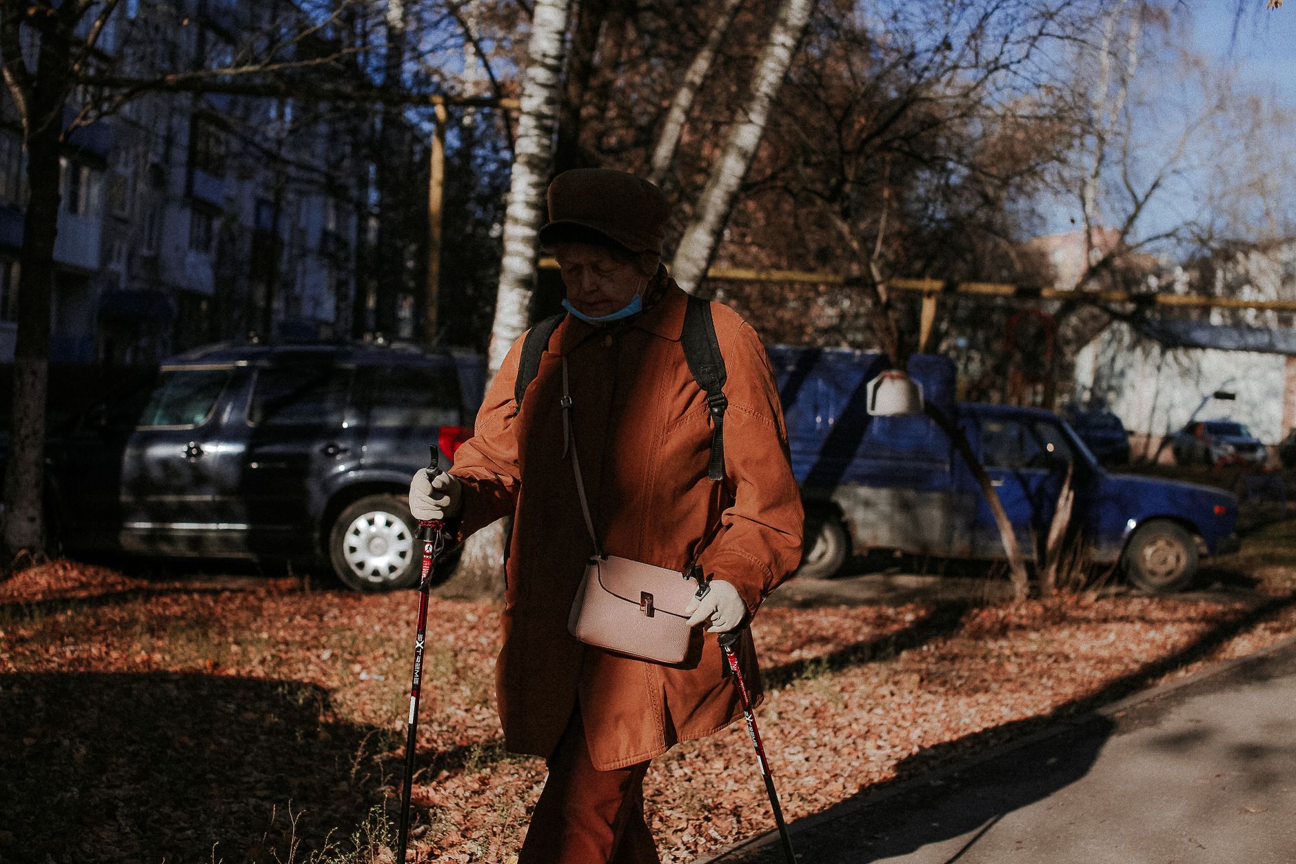 Une femme âgée marche avec des bâtons dans un parc en automne