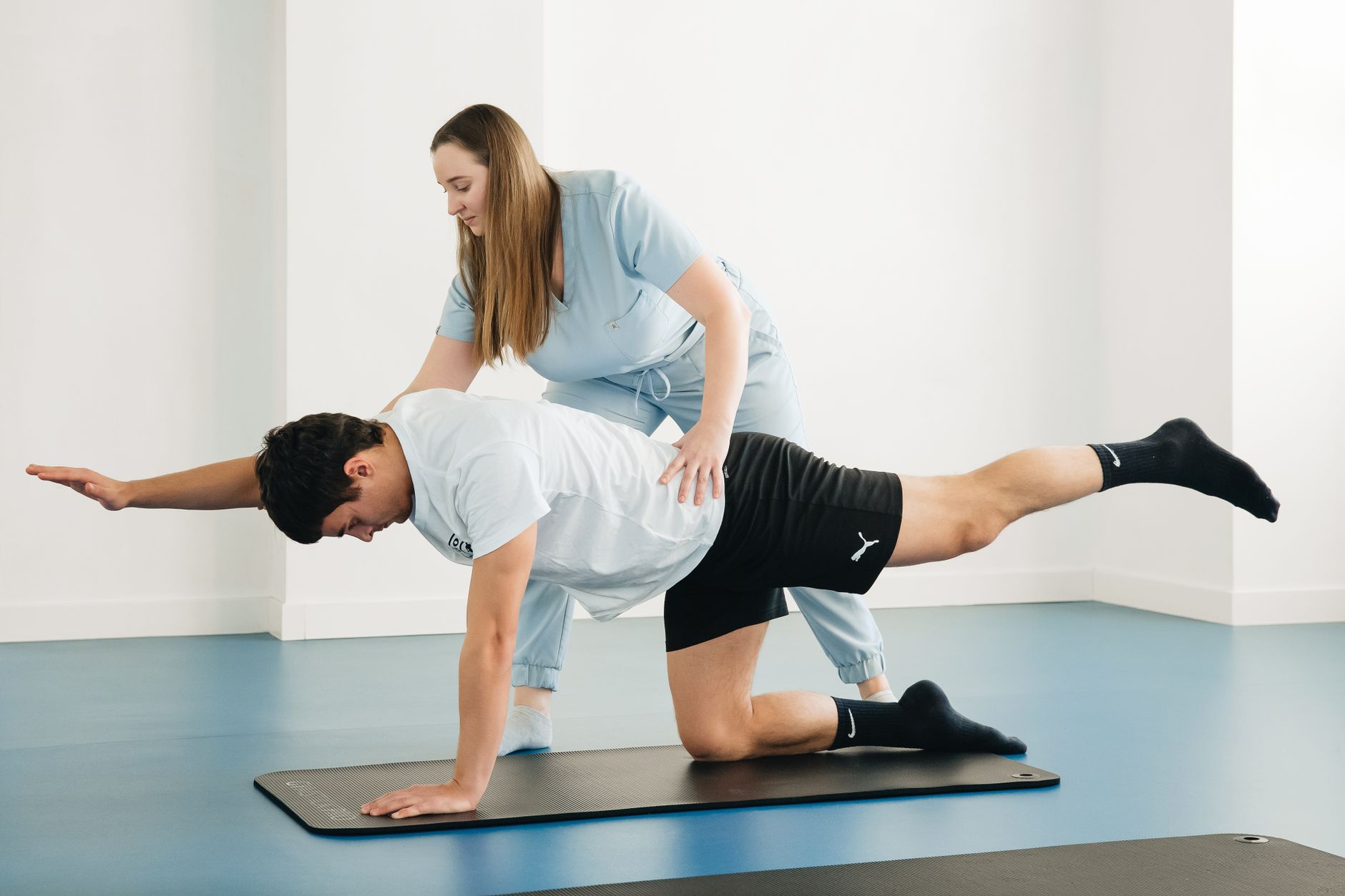 Un kinésithérapeute guide une patiente dans des exercices de rééducation