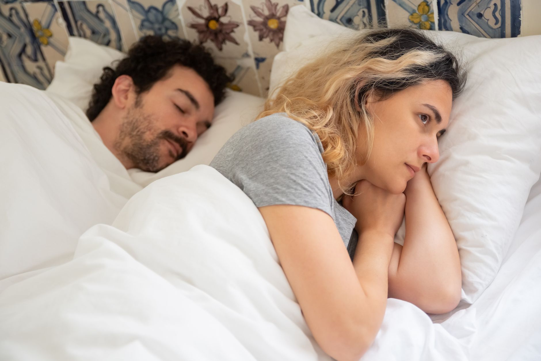Femme éveillée dans son lit à côté de son partenaire endormi
